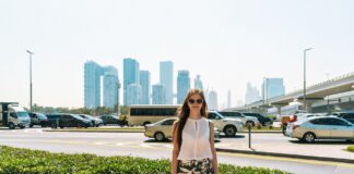 Stylowa kobieta idąca ulicą Dubaju na tle miejskiej panoramy