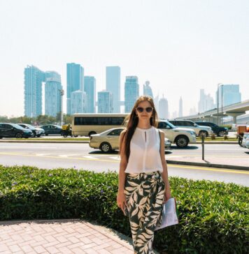 Czy Dubaj jest bezpieczny dla kobiet podróżujących solo? Praktyczne wskazówki Stylowa kobieta idąca ulicą Dubaju na tle miejskiej panoramy